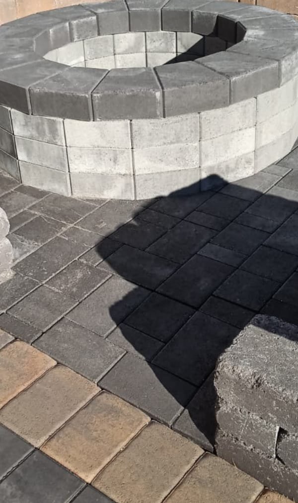 A circular paver fire pit built on a multi-tone paver patio.